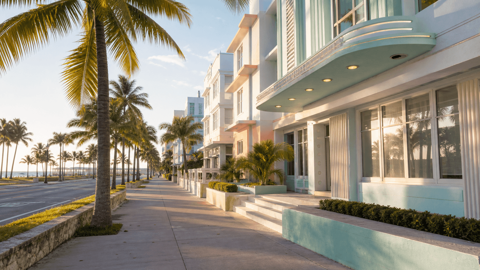 Rounded pale facade beside palms and a sidewalk