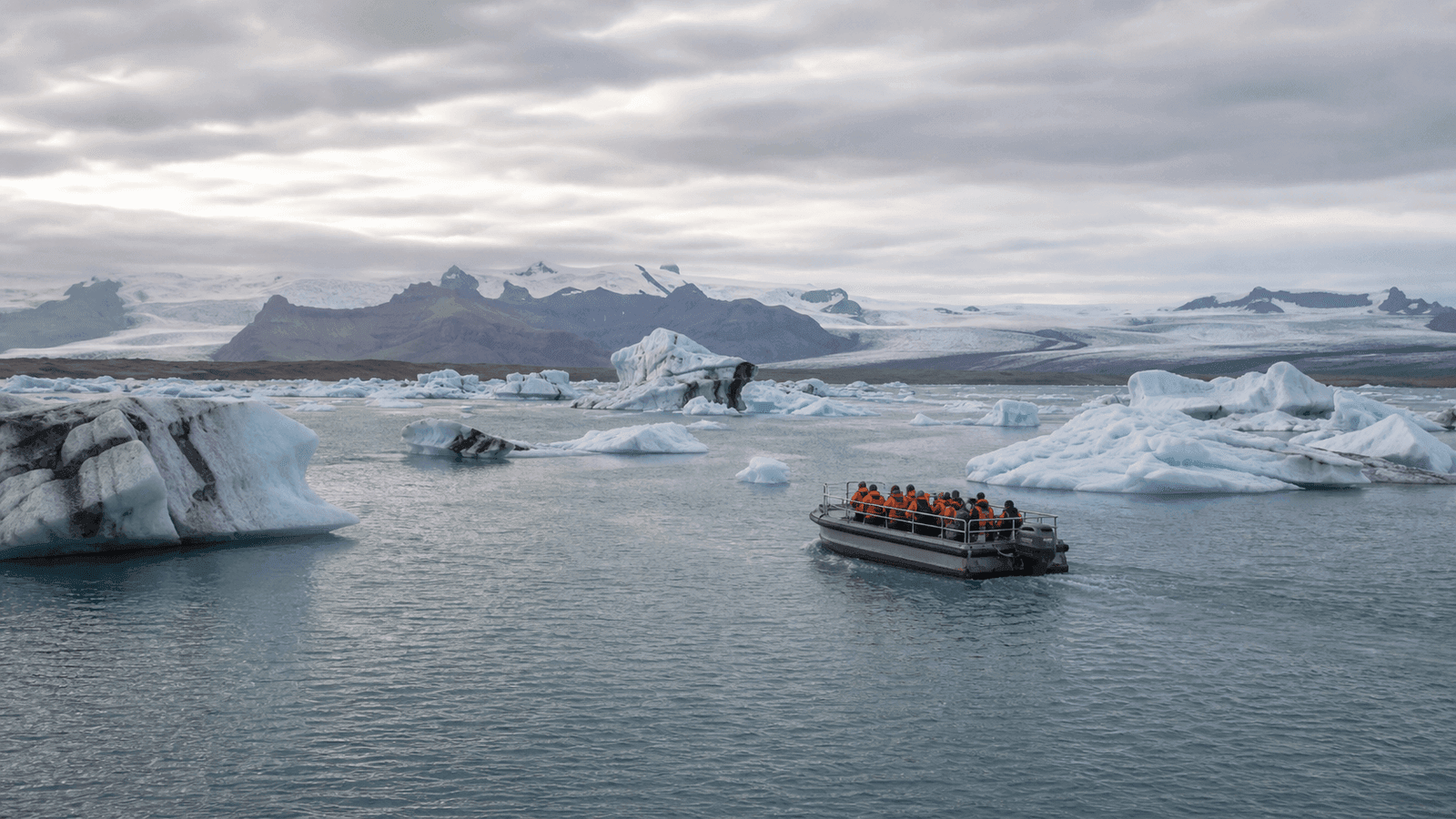 Boat with people in orange vests and icebergs