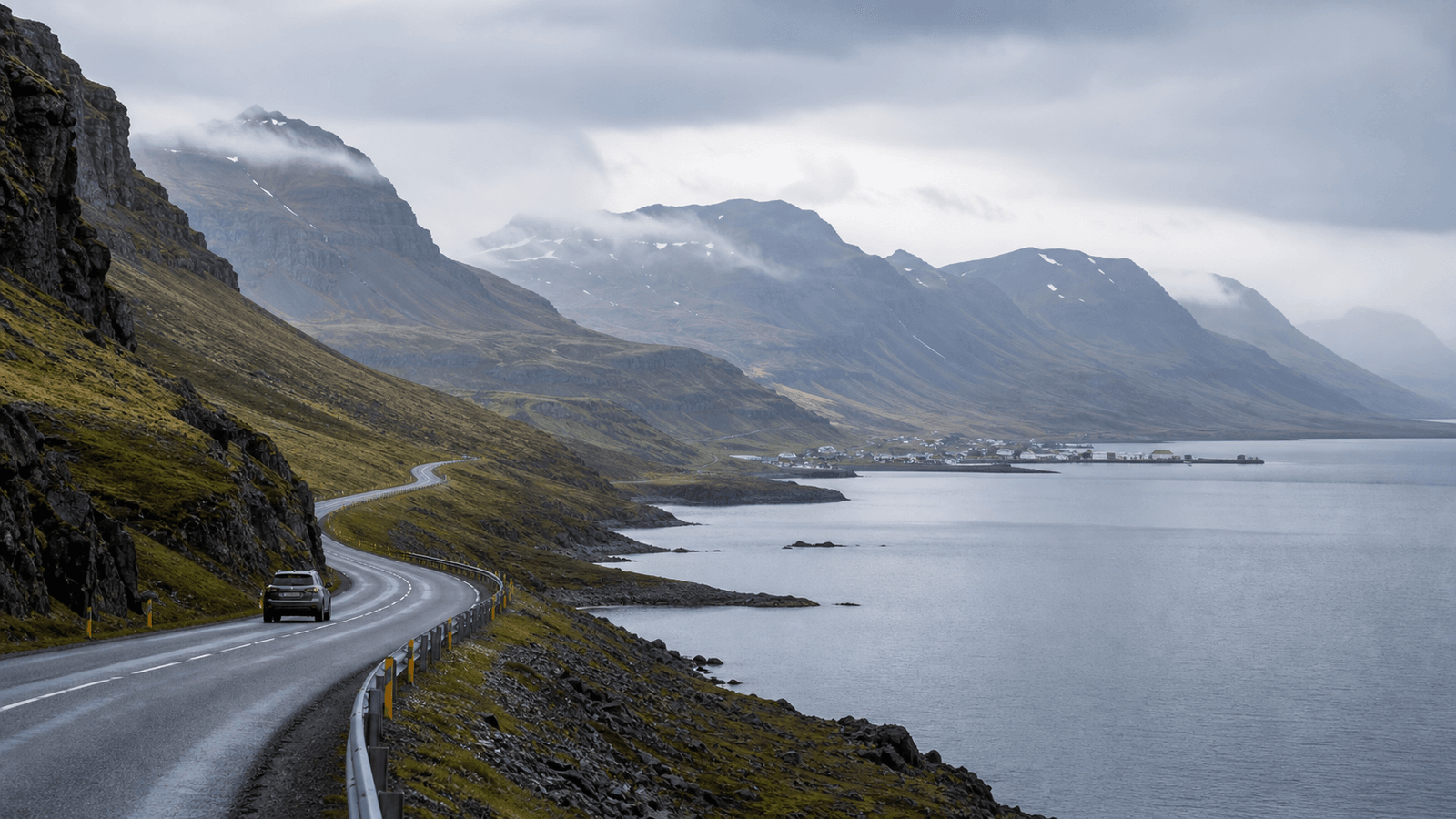 Car on a road beside a fjord