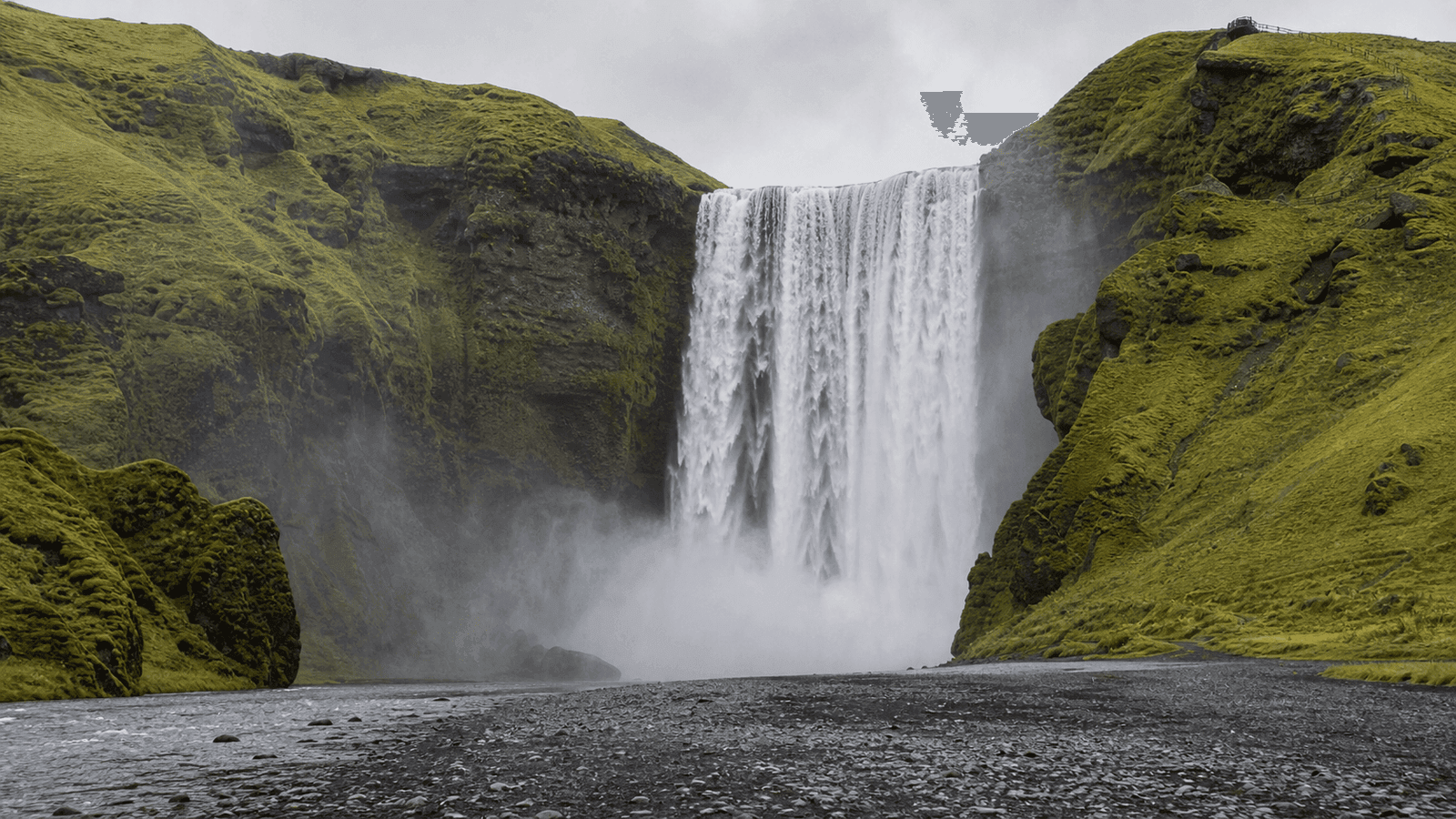 Broad waterfall beneath green cliffs