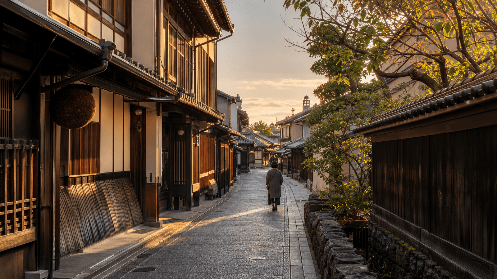 A person walks along a narrow street of wooden houses in evening light