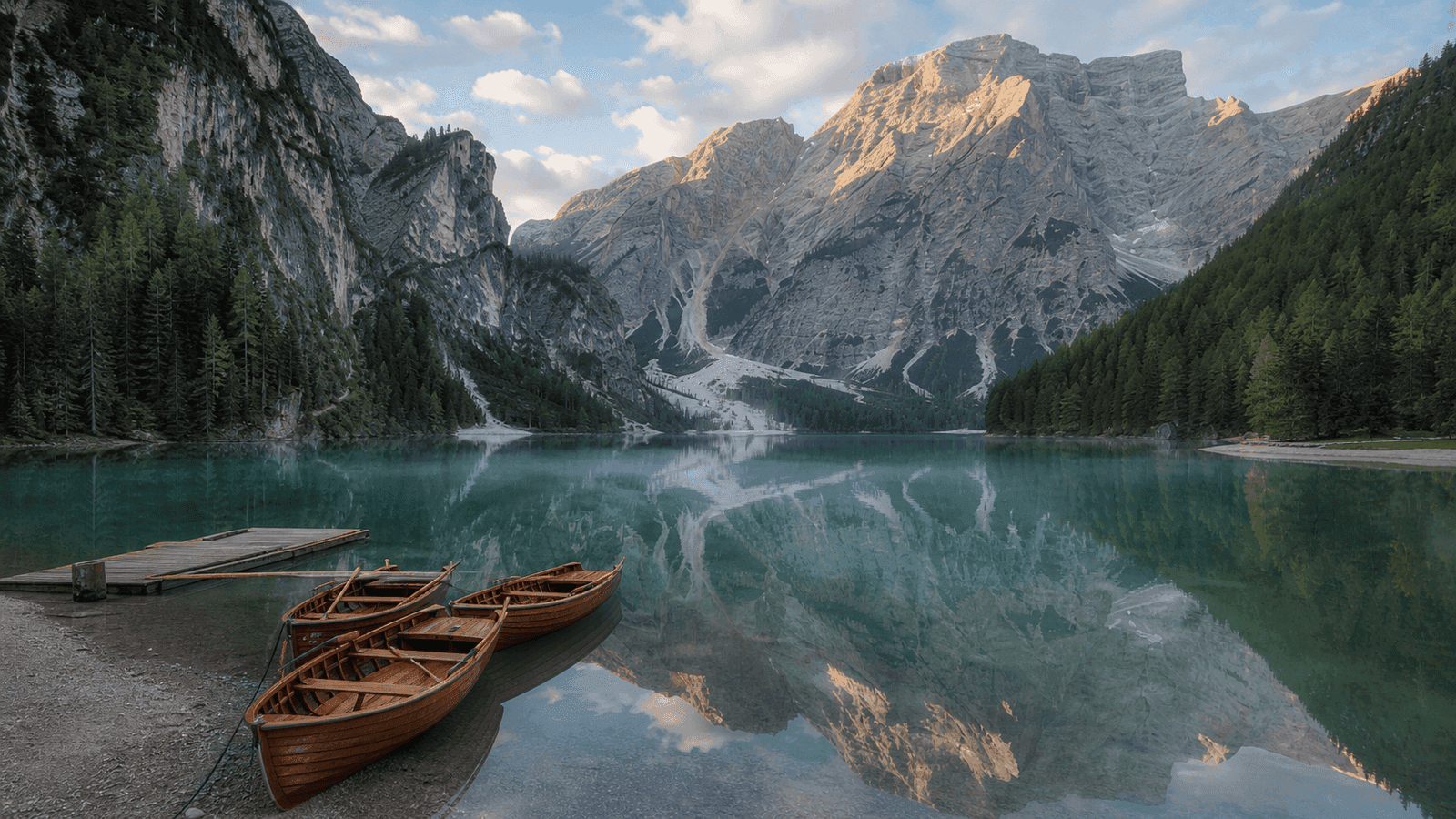 Rowing boats on a turquoise mountain lake beneath rock walls.