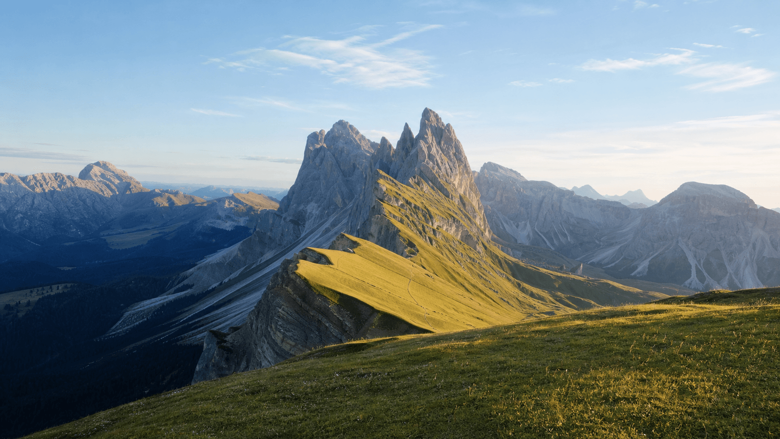 Green, steep-sided mountain ridge leading towards rocky peaks.