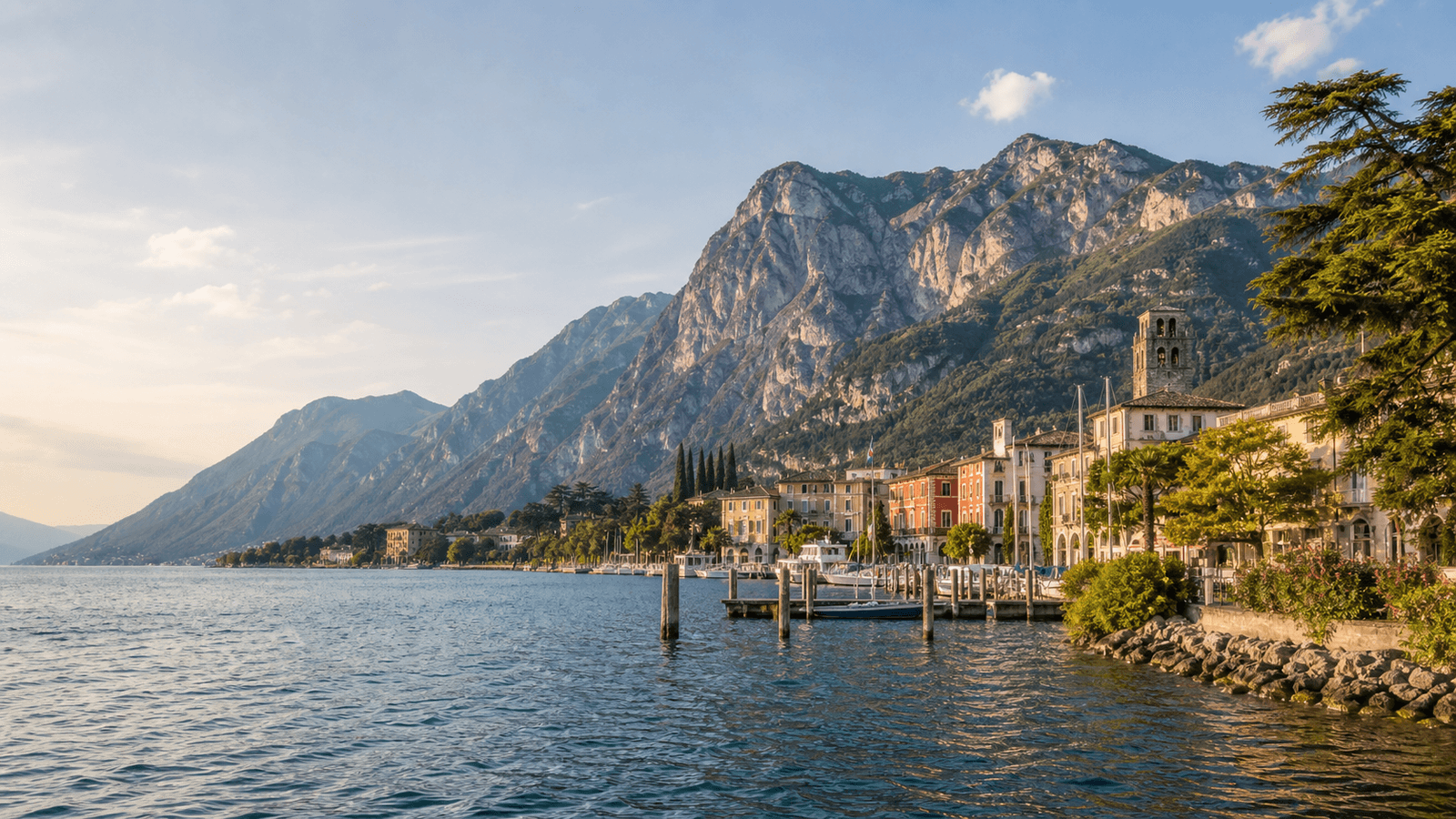 Lakeshore buildings and landing stages below steep mountains.
